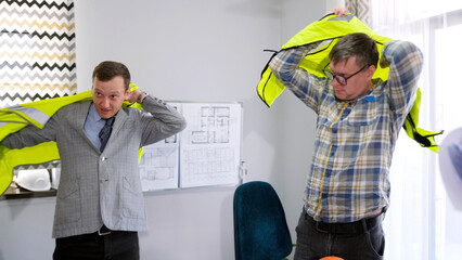 The foreman and the chief civil engineer go to inspect the facility. Two men put on green safety vests to work at a construction site