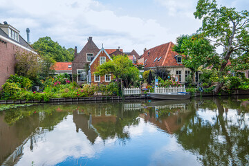 Fototapeta premium Picturesque canal with traditional Dutch buildings, trees and flowers. EDAM, NETHERLANDS.