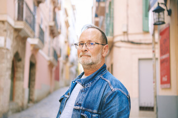 Portrait of mature 55 - 60 year old man posing outdoors, wearing glasses