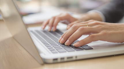 close-up of woman&rsquo;s hands typing on clean laptop keyboard with shallow depth of field