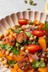 Autumn warm chickpea and roasted pumpkin salad with fresh cherry tomatoes and herbs. Vegan meals
