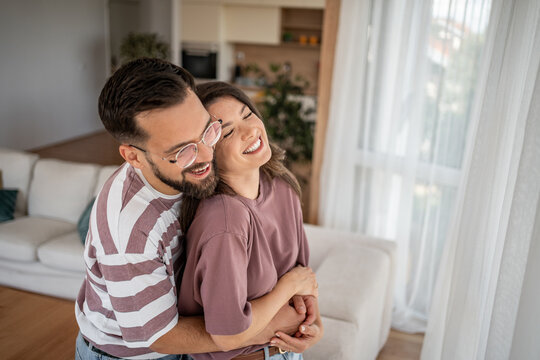 Happy couple embracing and laughing together in living room