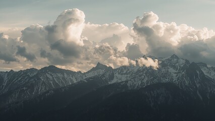 Mountain range with snow capped peaks under a cloudy sky landscape.