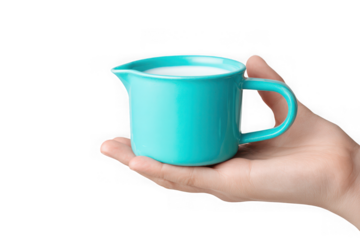 Hand holding a small turquoise creamer filled with milk.