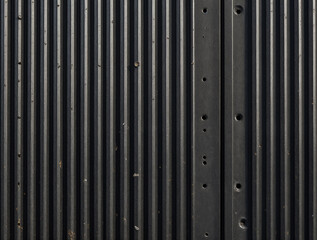 A brooding wall of black corrugated steel where light whispers and shadows linger, echoing strength, edge, and architectural cool.