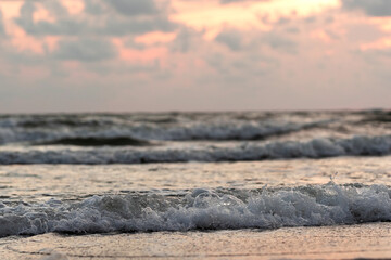 Sunset by the sea. Dramatic sky with clouds, painted by the sun in yellow, orange colors. The whitened Baltic Sea
