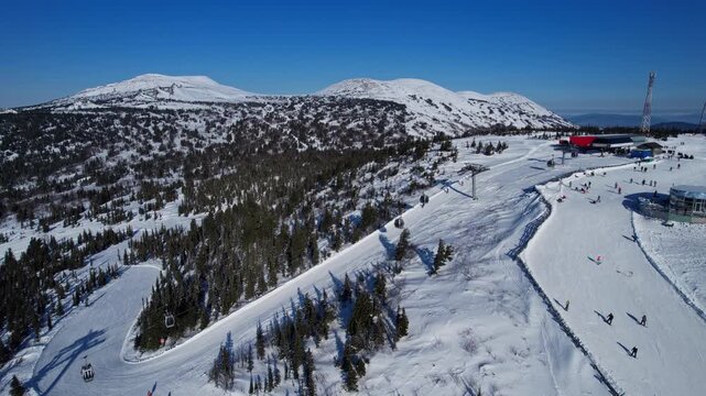 Aerial top view snowboarders are riding down slope in Sheregesh ski lift resort, winter landscape mountain, Russia Kemerovo region.