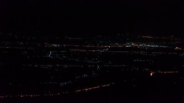 The multi colored city lights shine brightly in the pitch black darkness. Video was taken from a high mountaintop giving a panoramic view of the city under the pitch black sky. At Lom Kao Phetchabun.
