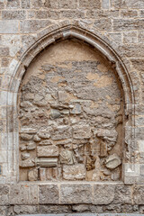 Fototapeta premium Ventana de forma ojival cerrada con piedras y restos arqueológicos de una iglesia.