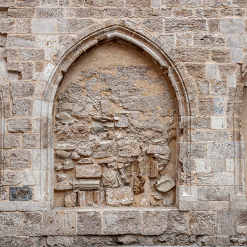 Ventana de forma ojival cerrada con piedras y restos arqueol&oacute;gicos de una iglesia.
