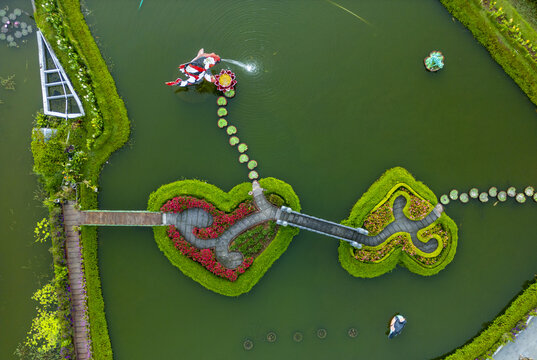 Aerial view of heart-shaped gardens and walkways reflect in the still water of Danau Beratan, Candikunging, Bali, Indonesia.