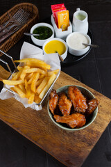 Peruvian Gastronomy, A plate of fried chicken wings and a bowl of fries sit on a wooden cutting board