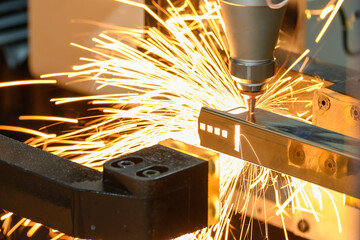 Close up scene the fiber laser cutting machine cut the square shape stainless steel tube with sparkling light.