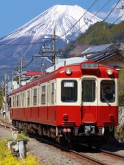 Train passes traditional village with Mt. Fuji in background
