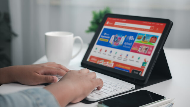 Shopping online concept, Close-up of human hands typing on wireless keyboard while shopping online on tablet screen, e commerce concept, indoor home office setup.