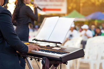 Pianist male hands playing electric piano with the band on stage. Classical concert, performance rehearsal, show. Learning to play a musical instrument. Hands of musician or artist play synthesisers.