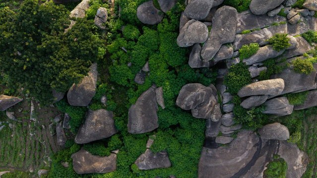 Aerial view of massive grey boulders nestled amongst vibrant green vegetation, creating a textured landscape from above, Jos, Plateau, Nigeria.