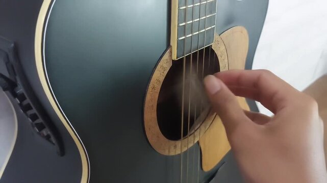 an elegant black acoustic guitar made of rosewood, with six steel strings that produce a melodious sound.