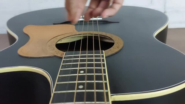 an elegant black acoustic guitar made of rosewood, with six steel strings that produce a melodious sound.