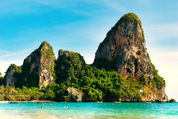 Railay Beach, Krabi Province, Thailand, 01 August 2025 : The beautiful seascape of sand beach, blue sky, sea and limestone mountains at seashore. Boats on turquoise waters. picture perfect hot day.
