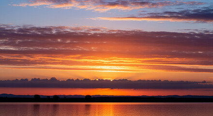Obraz premium Vibrant Sunset Landscape: Colorful Sky, Water Reflection, Scenic Vista