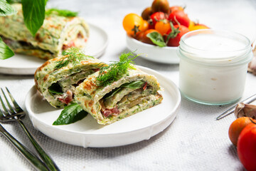 Appetizing zucchini roll with tomatoes and garlic on a light background