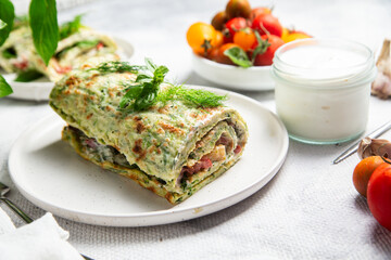 Appetizing zucchini roll with tomatoes and garlic on a light background