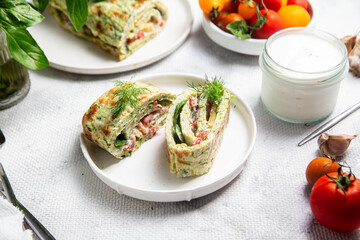 Appetizing zucchini roll with tomatoes and garlic on a light background