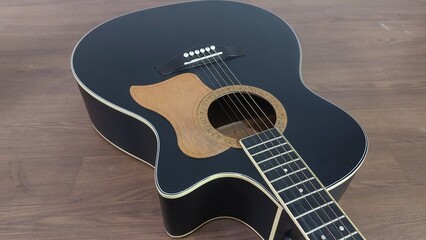 Fototapeta premium an elegant black acoustic guitar made of rosewood, with six steel strings that produce a melodious sound.