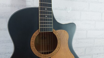 an elegant black acoustic guitar made of rosewood, with six steel strings that produce a melodious sound.