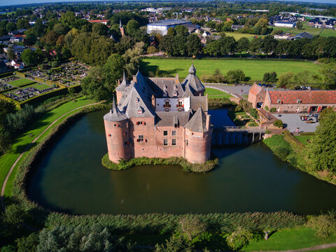 Aerial view of a medieval castle with a surrounding moat reflecting the clear sky, contrasting with the lush green landscape, Helmond, North Brabant, Netherlands.