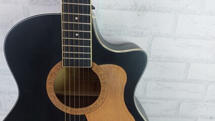 an elegant black acoustic guitar made of rosewood, with six steel strings that produce a melodious sound.