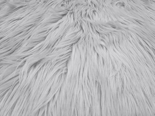 Background of light gray shaggy faux fur fabric. Shaggy faux fur fabric made of synthetic fibers for decoration or DIY projects. Textile material to imitate and replace the texture of real animal fur.