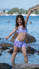 A sweet little girl child joyfully playing in the sea during vacation, enjoying the summer