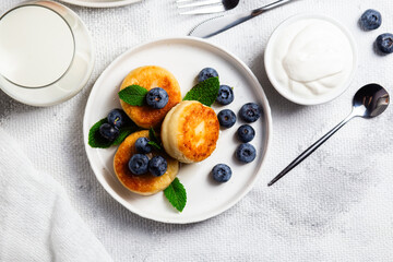 Appetizing cheesecakes with sauce and blueberries on a light background