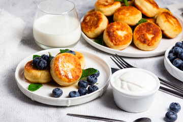 Appetizing cheesecakes with sauce and blueberries on a light background