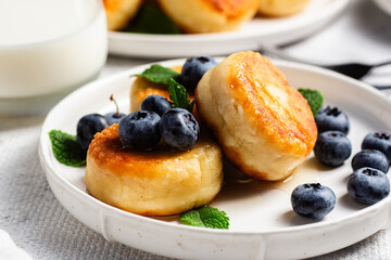 Appetizing cheesecakes with sauce and blueberries on a light background