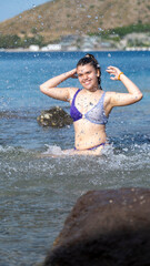A slightly overweight girl happily playing in the sea during vacation