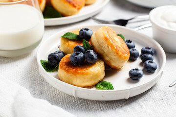 Appetizing cheesecakes with sauce and blueberries on a light background