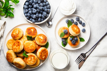 Appetizing cheesecakes with sauce and blueberries on a light background