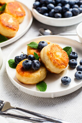 Appetizing cheesecakes with sauce and blueberries on a light background