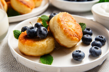 Appetizing cheesecakes with sauce and blueberries on a light background