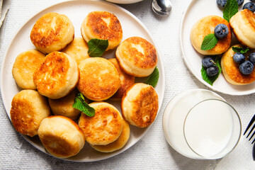 Appetizing cheesecakes with sauce and blueberries on a light background