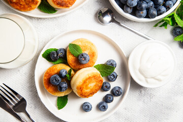Appetizing cheesecakes with sauce and blueberries on a light background