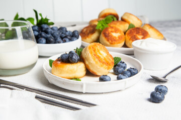 Appetizing cheesecakes with sauce and blueberries on a light background