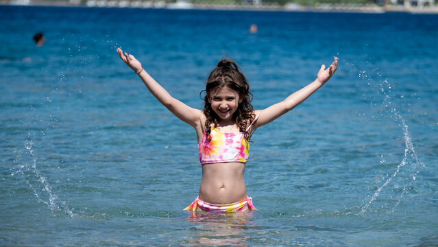 A sweet little girl child joyfully playing in the sea during vacation, enjoying the summer