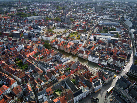 Aerial view of the Graslei and Korenlei, with their guildhalls reflecting in the Leie river, amidst a sea of red rooftops, Ghent, Flanders, Belgium.
