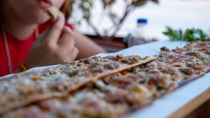 A girl child enjoying the taste of Turkish regional dish, meat pide, during vacation