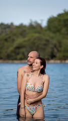 Obraz premium A young couple on vacation embracing each other romantically in the sea, posing for a photo