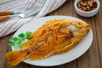 Deep fried red tilapia fish on white plate and dipping sauce